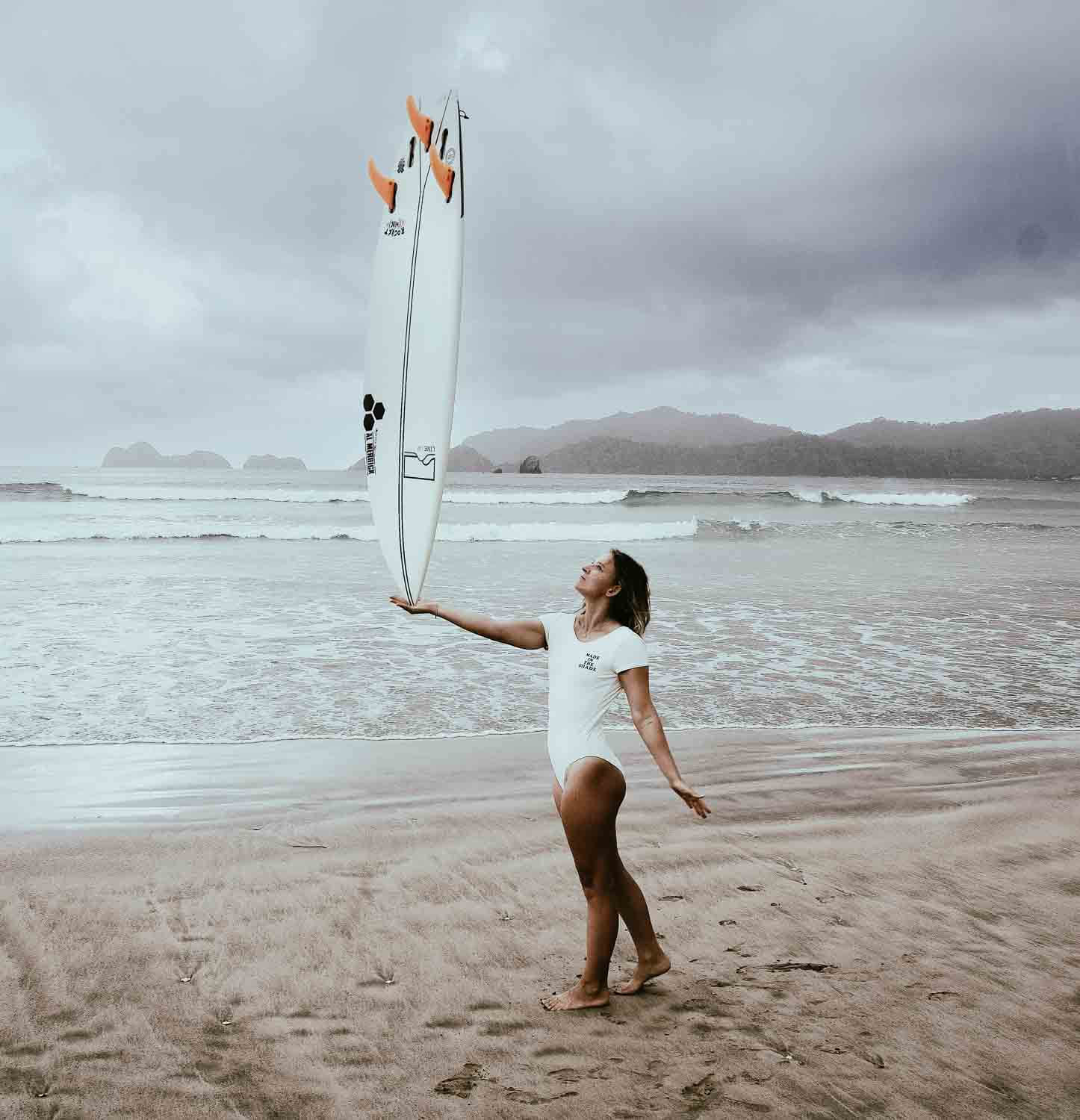 Lea Filip holding her surfboard on one hand at the beach in Red Island, Indonesia